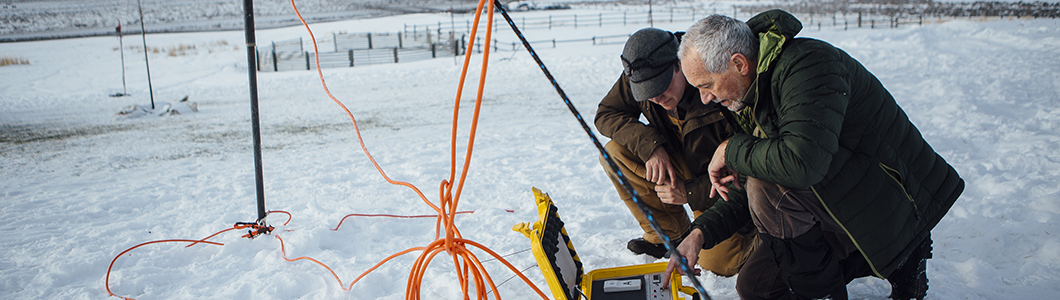 Researchers examine equipment readings in a winter field