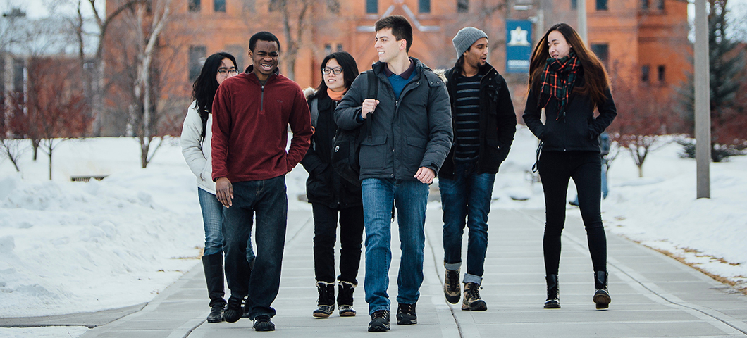 A group of students walks in front of Montana Hall in winter.