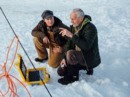 two men discussing project while crouching on the snow