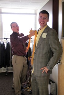 A student holds up a tie to another student at the Executive's Closet event