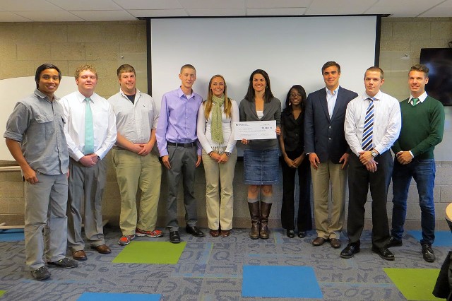 Nine students present a check to a person from Warriors and Quiet Waters