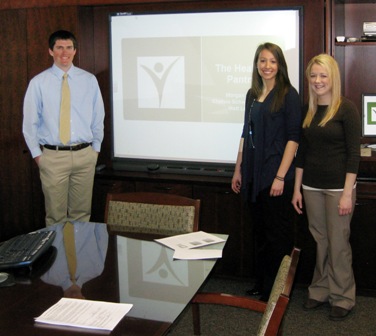 Three students stand in a conference room