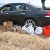 Plastic and paper bags lying on the ground next to a car