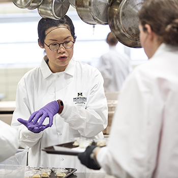 two women talking to each other in white lab coats