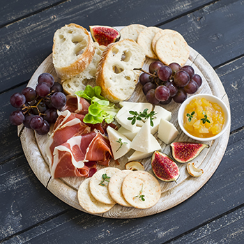 charcuterie platter with sliced bread, meat, cheese, and fruit