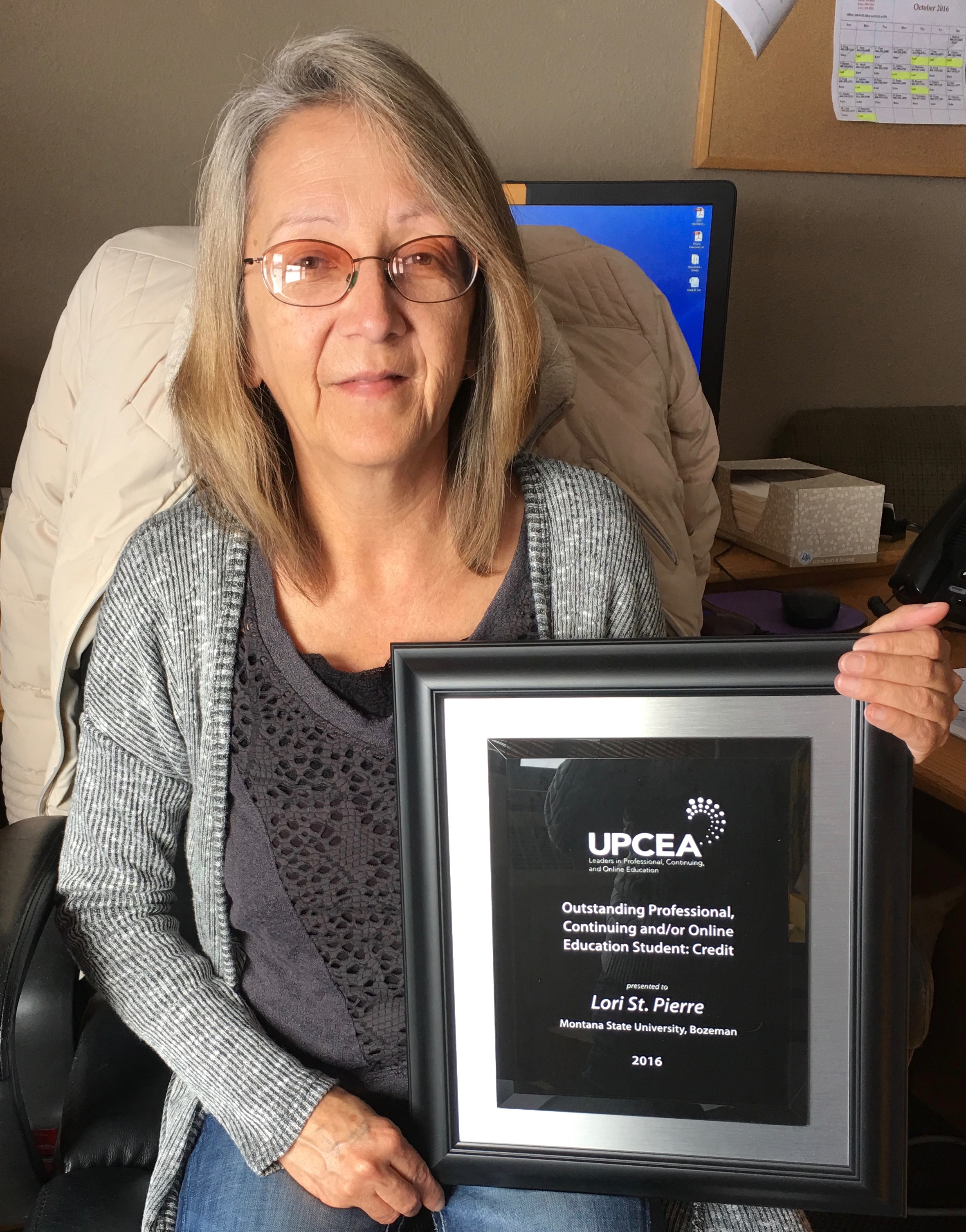 Lori St. Pierre in her office with award plaque