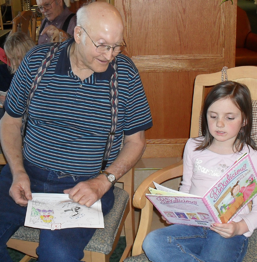 Elderly man reading stories to young girl