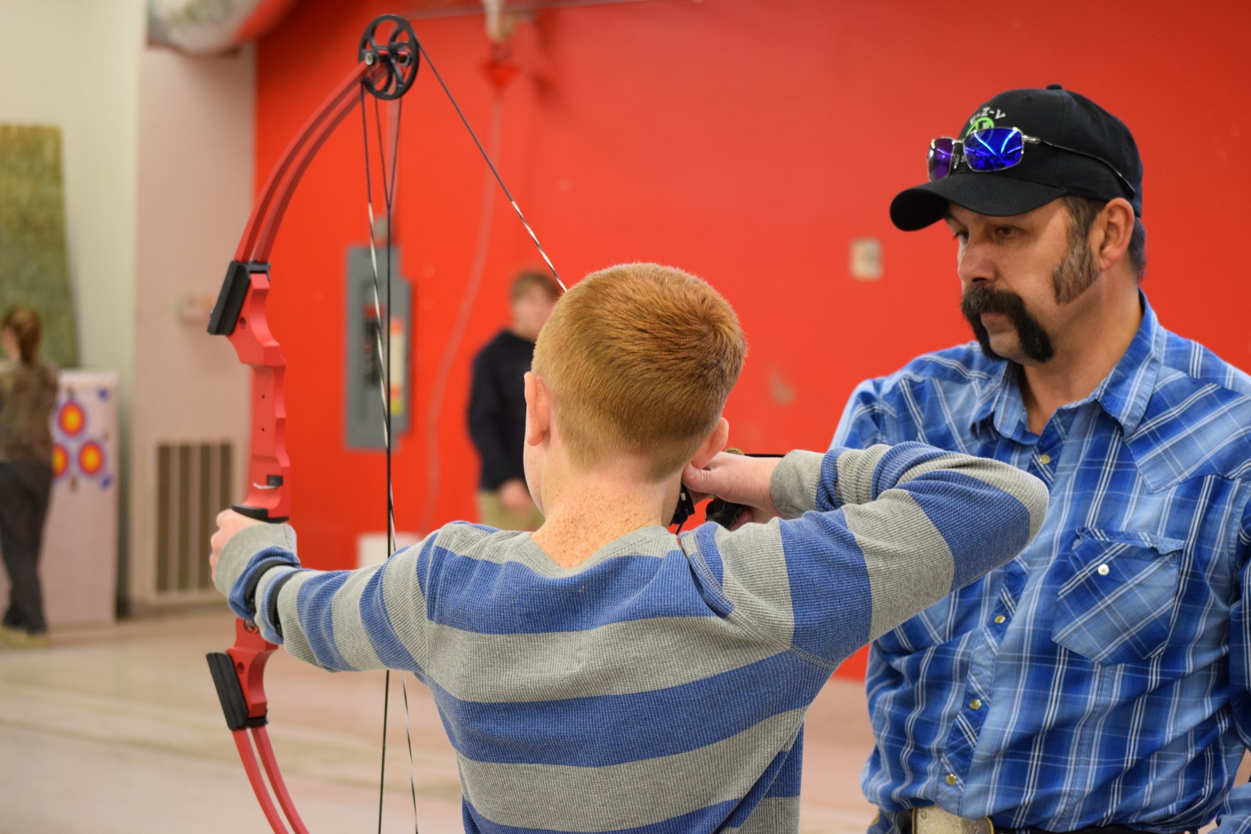 4-H leader coaches a young archer
