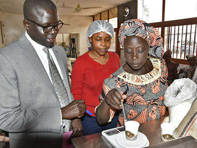 One man and two women are weighing product on a scale