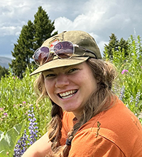 Annie Binion profile photo against a backdrop of a Montana hillside covered with wildflowers
