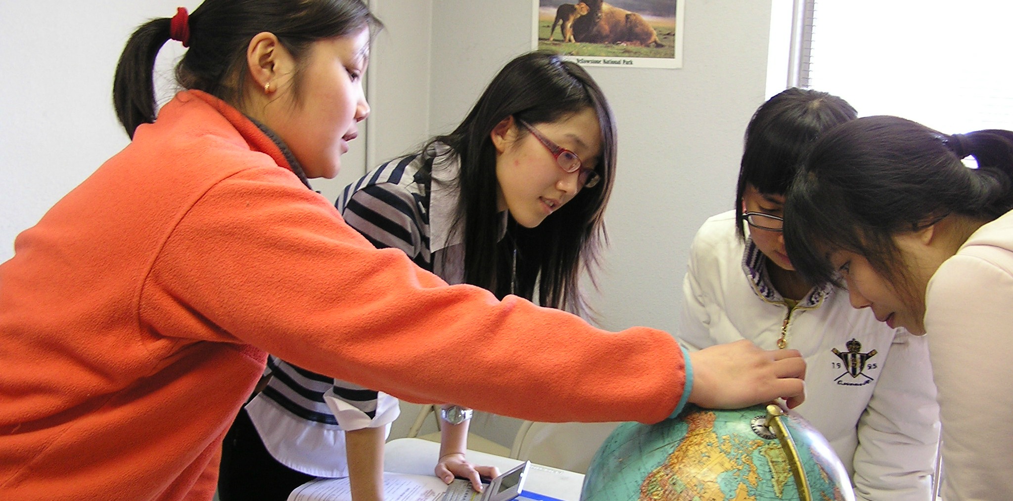 International Students looking at a globe 