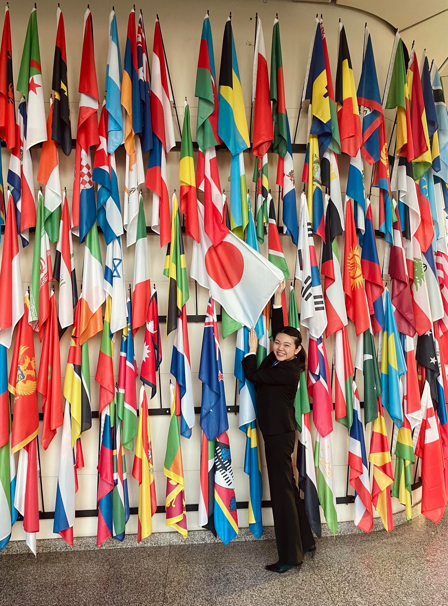 Yui Nakama surrounded by world flags, holding Japanese flag