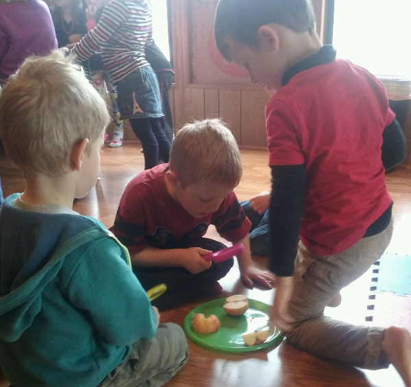 children investigating apple slices with magnifying glasses children investigating apple slices with magnifying glasses