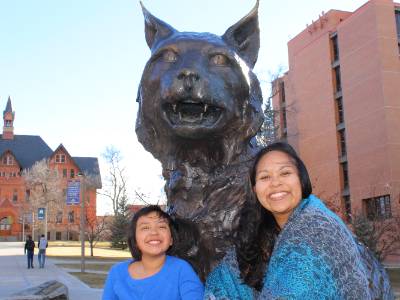 Elva and her daughter Rebbeca sitting next to the bobcat statue in front of Montana and Leon Johnson Halls