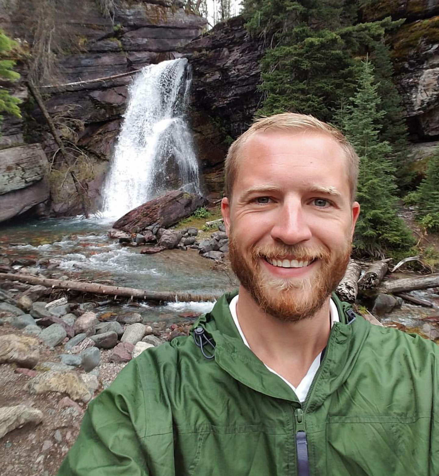 Mark Hedinger in a green jacket in front of a waterfall