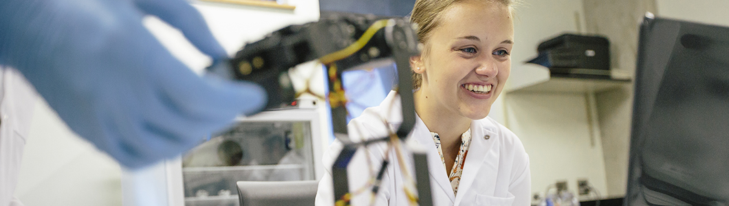 Student smiling in a lab coat