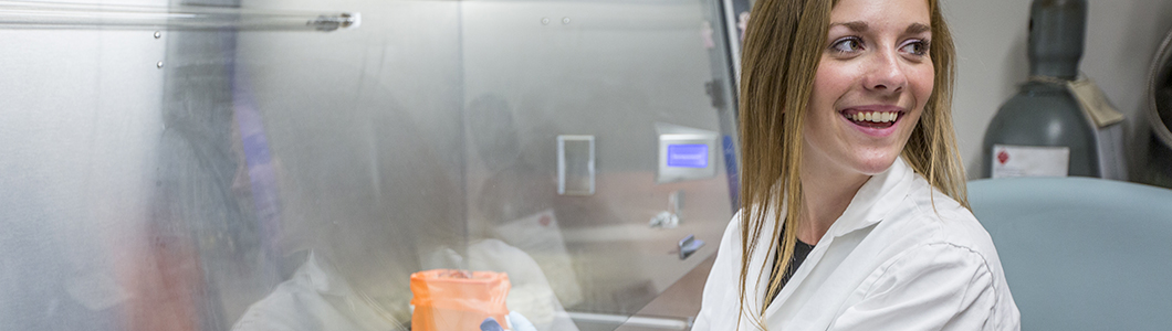 A female scientist looks away from a fume hood in excitement.