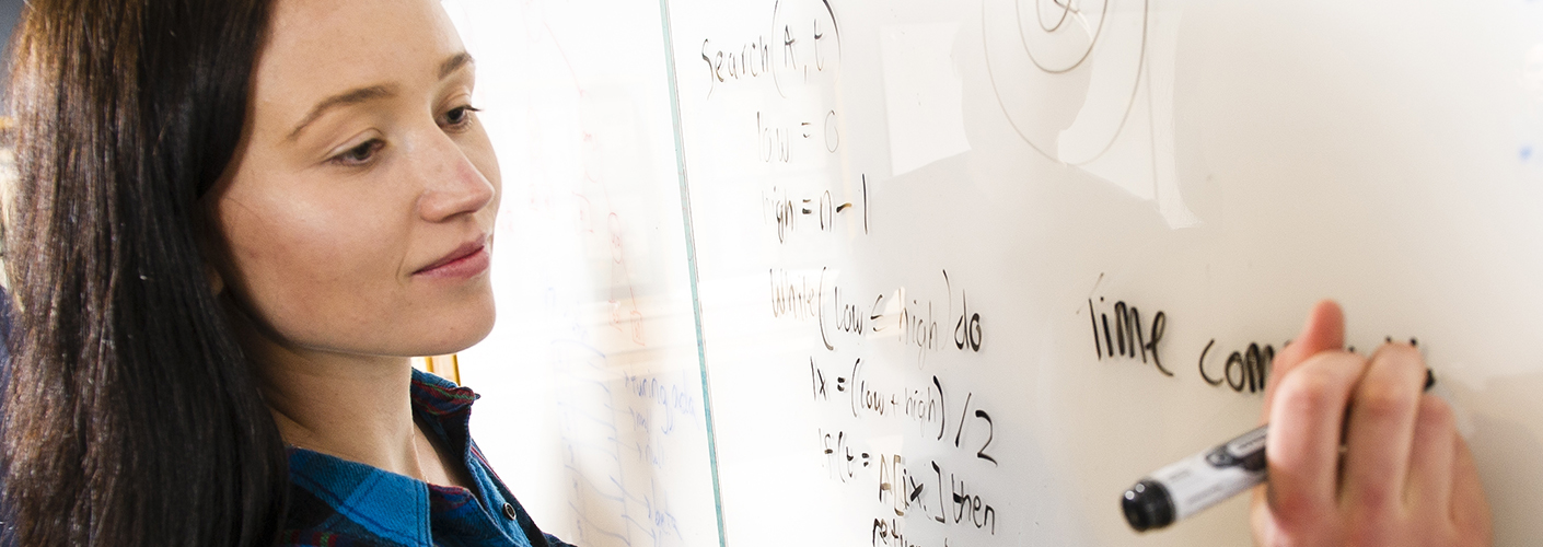 A young woman writes search logic out on a whiteboard.