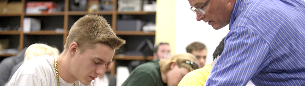 Two young men, one Caucasian and one African-American, discuss something shown on a laptop.