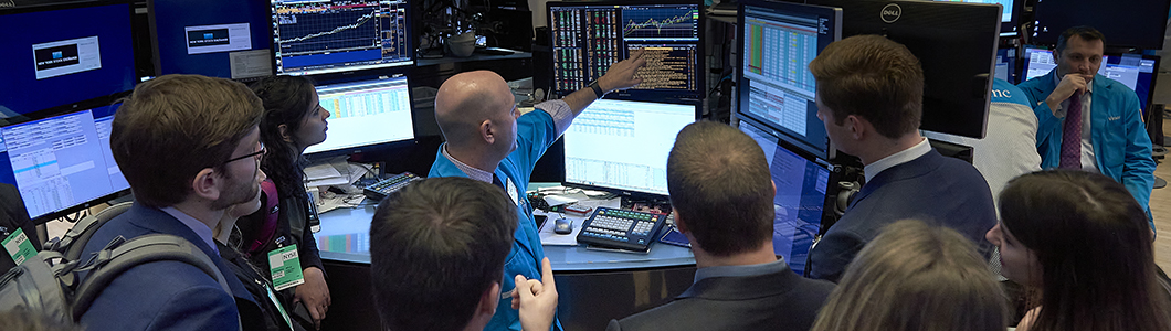 A group of students listen as the executive floor governor of Wall Street gives a tour of the trading floor.