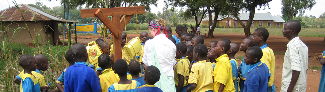 A student in a lab coat is surrounded by a classroom of students from Africa.