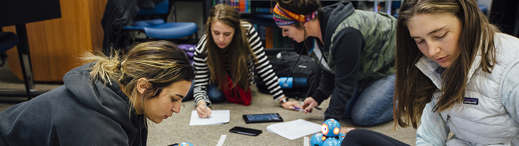 A group of young women work with simple robots.