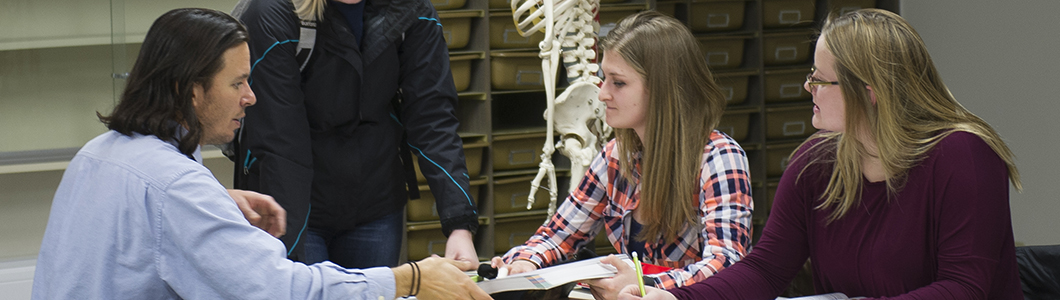 A group of students study in front of a skeleton.