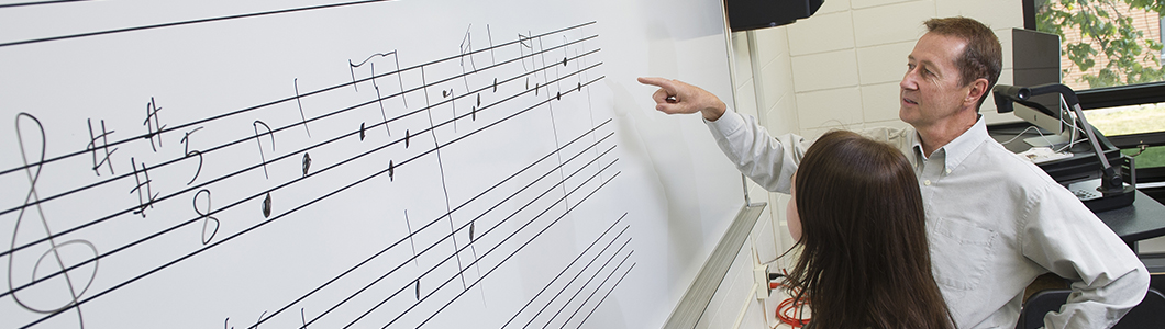 Two people discuss music notation on a whiteboard.