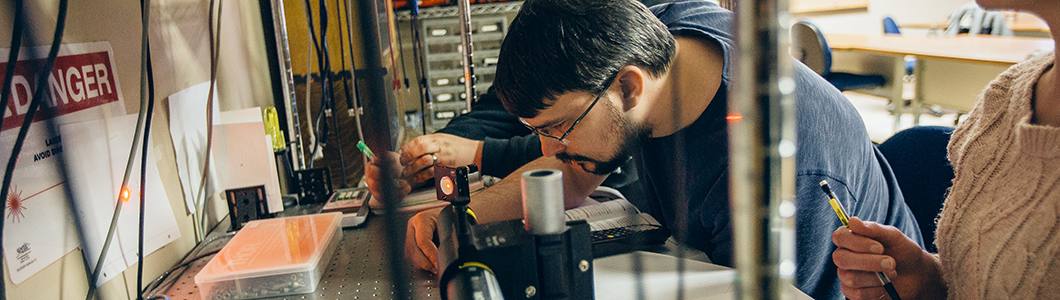 Two men observe measurements on photonics equipment.