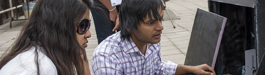 Two scholars monitor an expeirment in an outside lab test.