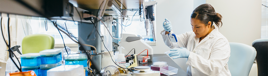 Researcher in lab coat examines petri dish