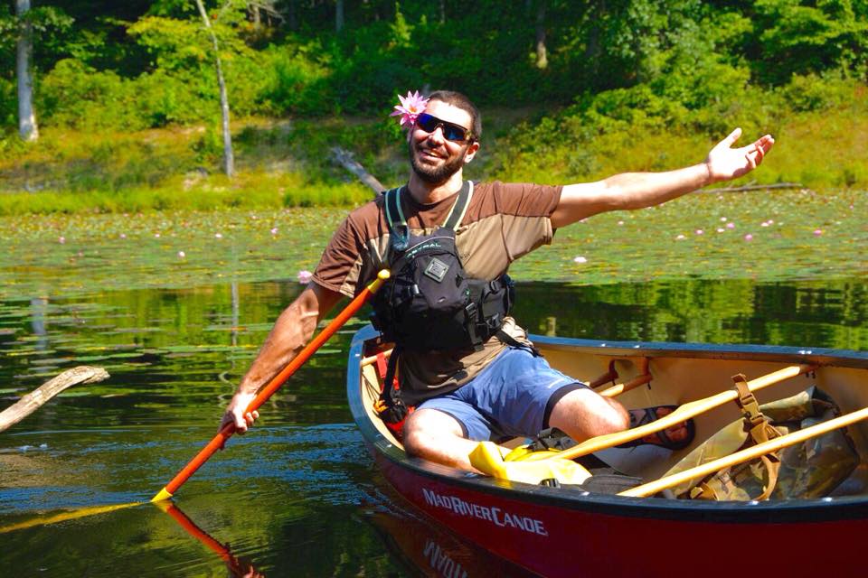 person smiling in a canoe with a flower in their hair. 