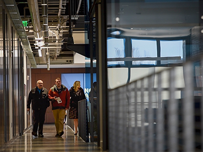 Three people walk down the hallway in Asbjornson Hall.