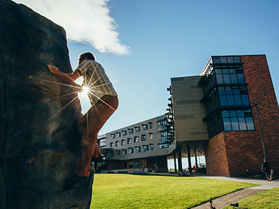 A student climbs a boulder at Yellowstone Hall.