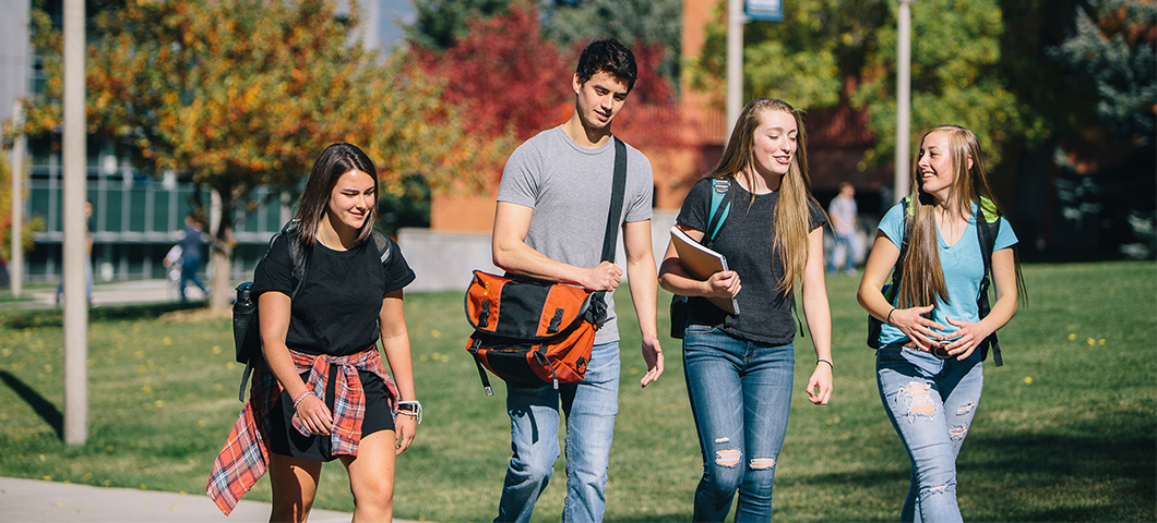 Four students walk across campus in the fall.