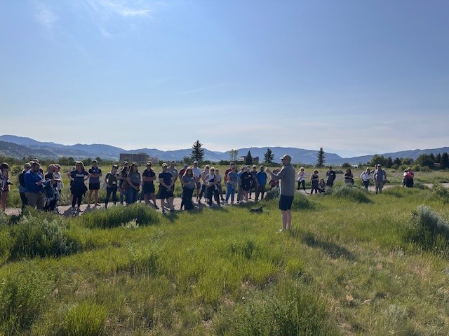 People standing in a line outside listening to an Admissions staff member speak
