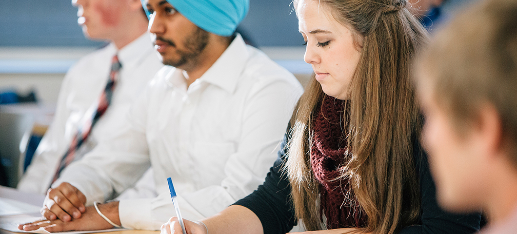 Students taking notes in a classroom on campus.
