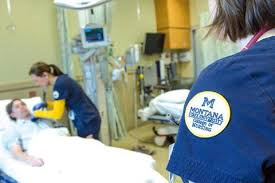 female nursing student working with a patient with nursing logo in the foreground