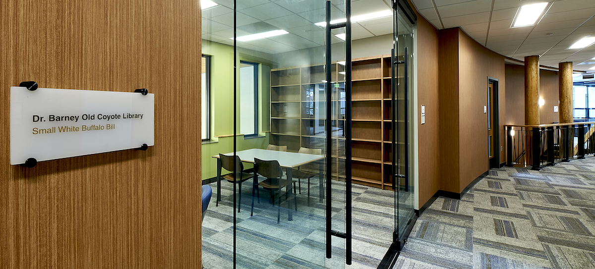 A small, brightly light library and study space is shown from an angled view.