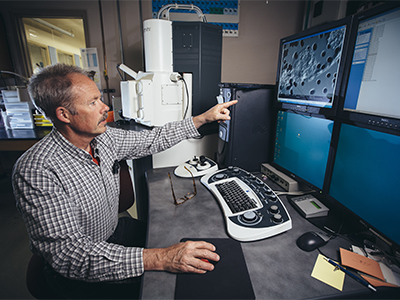 Bill Inskeep points to screen showing photo of bacteria