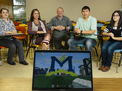 Group picture of Amanda Kotila, Elaine Westbrook, MSU associate education professor Nicholas Lux, Cotton Real Bird and Clarissa De Leon with open laptop with Minecraft on the screen