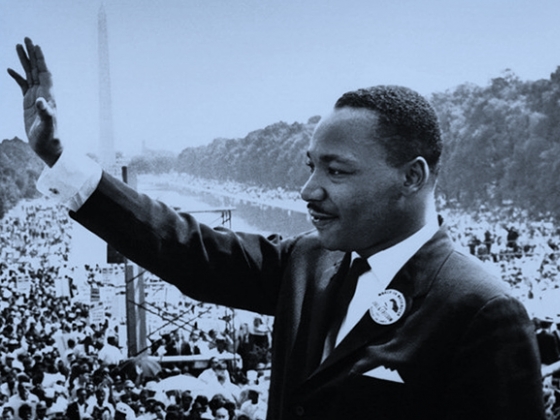 Martin Luther King Jr. waves to a crowd along the reflecting pool in Washington, D.C., in an archival black and white photo. | MSU