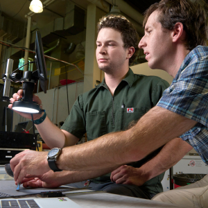 Two people looking through a microscope in a lab