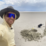 Zack Burton standing next to a hole in a dry lakebed