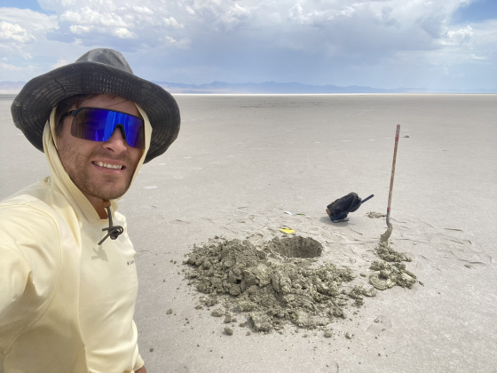 Zack Burton standing next to a hole in a dry lakebed | Photo by Zachary F. M. Burton