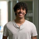 Lukas Kosel looks at the camera in front of a bright, out of a focus background
