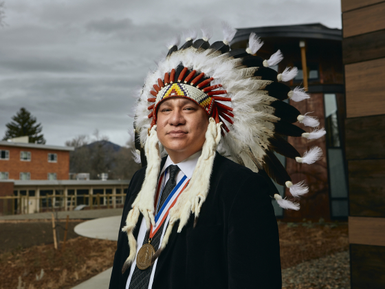 Leo Killsback poses for a portrait in a Headdress outside American Indian Hall. | MSU photo by Adrian Sanchez-Gonzalez
