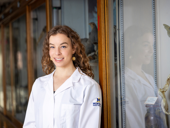 Ingrid Peters wearing an MSU logo lab jacket standing by a display case