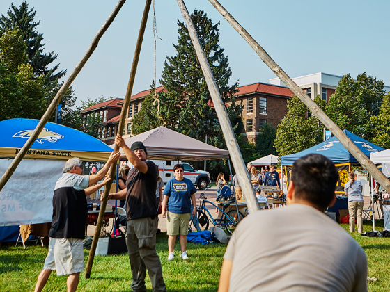 students raise support poles for a tipi on a lawn on MSU's campus | Adrian Sanchez-Gonzalez