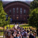 Scene of students walking amid tree-filled area.